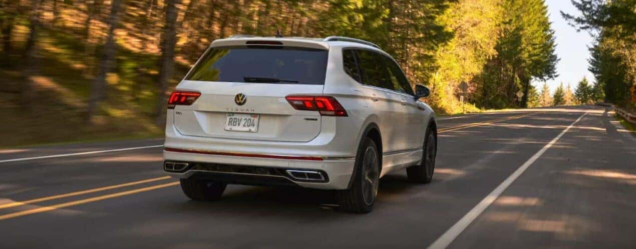 A white 2023 Volkswagen Tiguan is shown from the rear driving on an open road during a 2023 Volkswagen Tiguan vs 2023 Toyota RAV4 comparison.