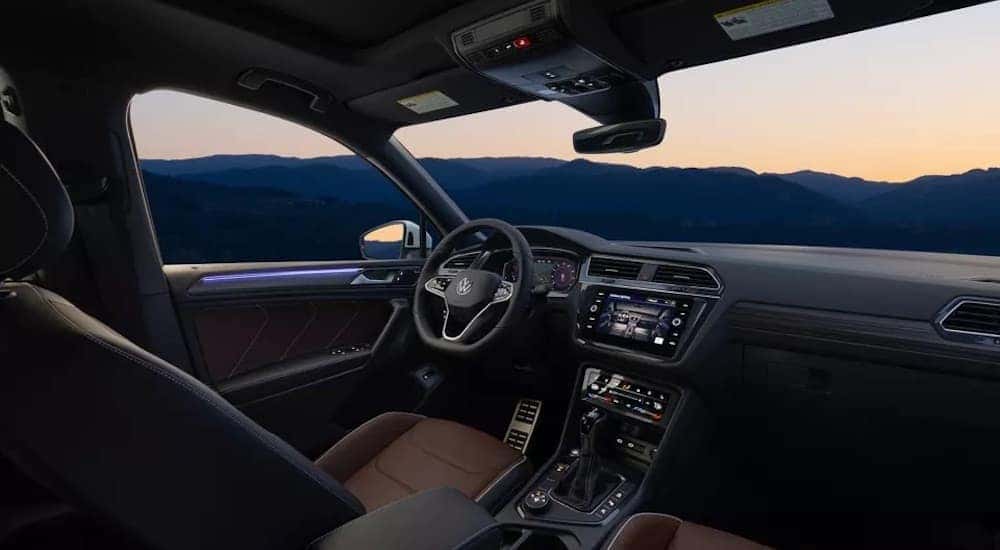 The black and brown interior of a 2023 Volkswagen Tiguan is shown from the passenger seat.