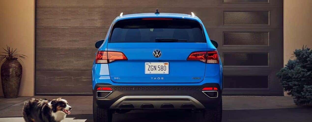 A red 2023 Volkswagen Taos is shown from the rear parked in a driveway.