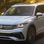 A white 2023 Volkswagen Tiguan SEL R-Line is shown driving on a road after winning a 2023 Volkswagen Tiguan vs 2023 Nissan Rogue comparison.