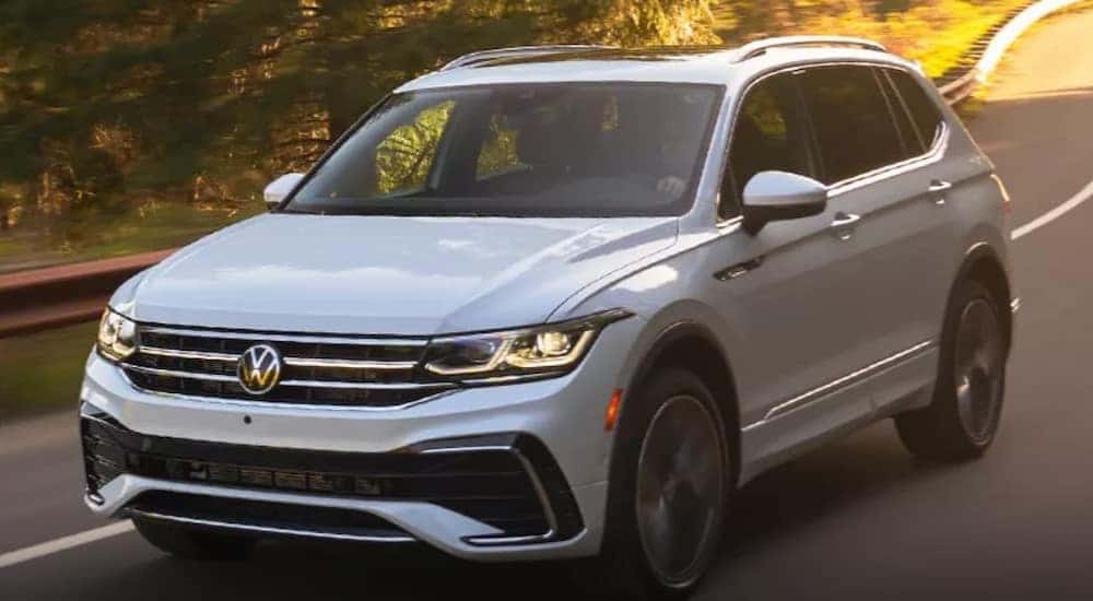 A white 2023 Volkswagen Tiguan SEL R-Line is shown driving on a road after winning a 2023 Volkswagen Tiguan vs 2023 Nissan Rogue comparison.