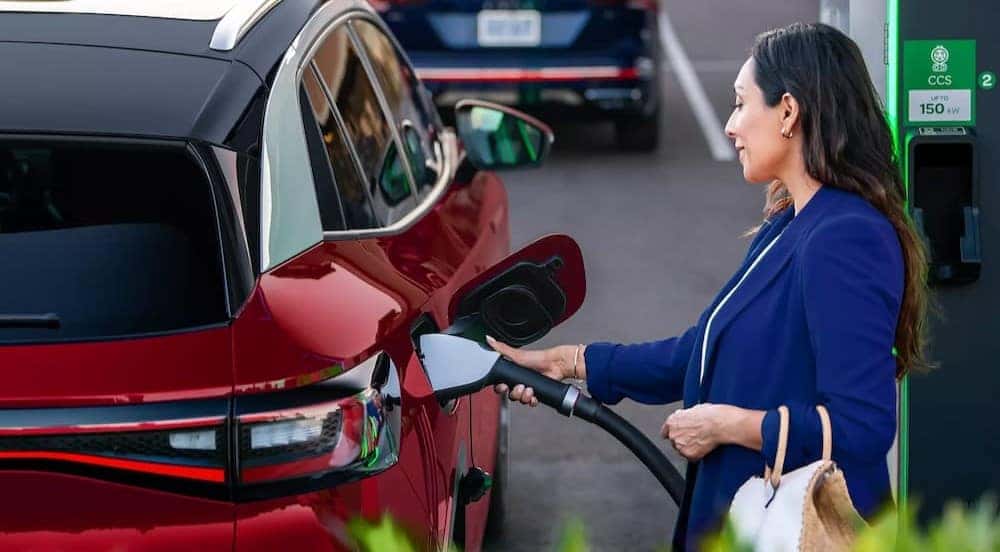 A person is shown charging a red 2023 Volkswagen ID.4.