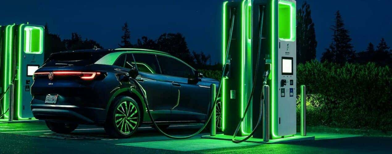 A blue 2023 Volkswagen ID.4 is shown parked at a charging station.