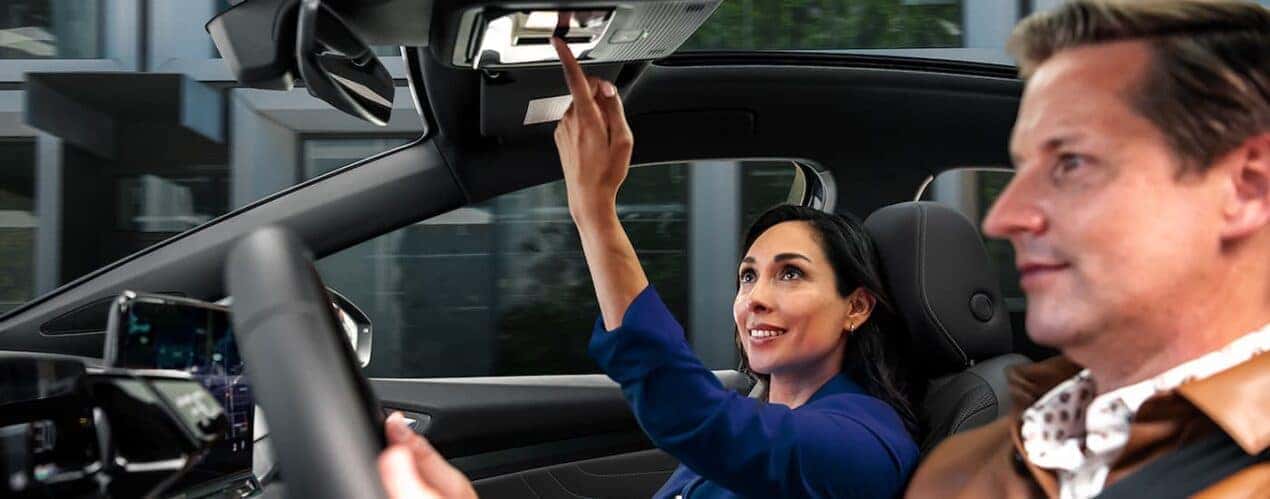 A woman opens the moon roof of the 2023 Volkswagen ID.4 as a man drives down a city street