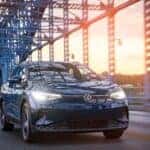 A blue 2023 Volkswagen ID.4 Pro is shown driving over a bridge.