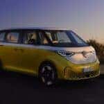 A yellow 2023 Volkswagen ID. Buzz is shown parked near a group of people.