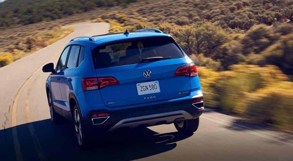 A blue 2024 Volkswagen Taos is shown driving on a highway.