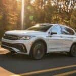 A white 2023 Volkswagen Tiguan is shown driving on a highway to visit a Fife Volkswagen dealer.
