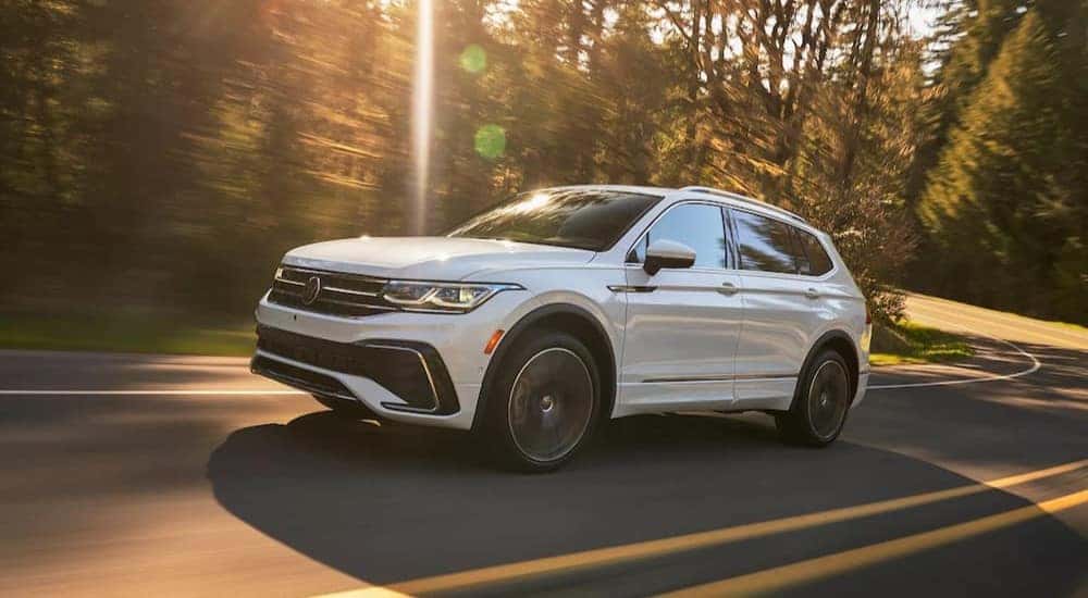 A white 2023 Volkswagen Tiguan is shown driving on a highway to visit a Fife Volkswagen dealer.