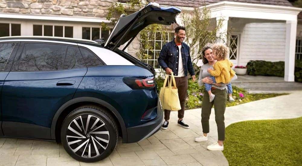 A family is shown loading cargo into the back of a blue 2024 Volkswagen ID.4 Pro S Plus.