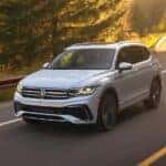 A white 2024 Volkswagen Tiguan SEL R-Line driving on a sunny road.
