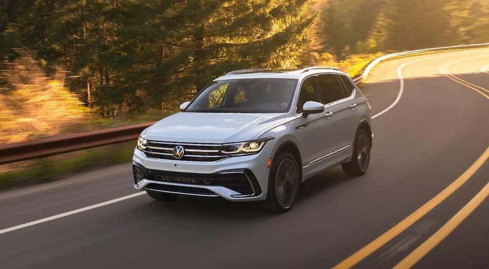 A white 2024 Volkswagen Tiguan SEL R-Line driving on a sunny road.