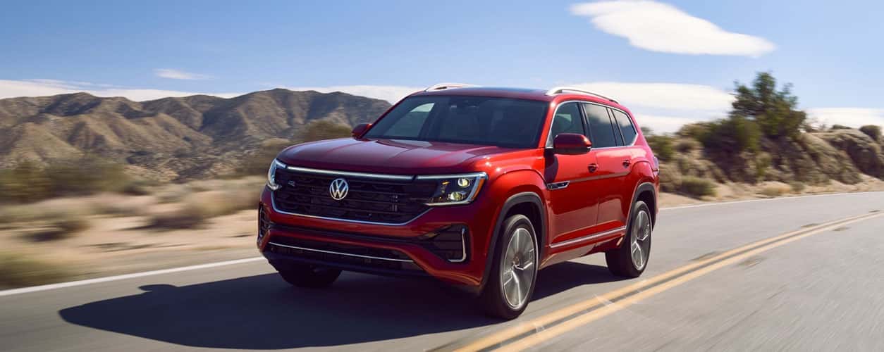 2026 VW Atlas in Aurora Red racing down a street with headlights on