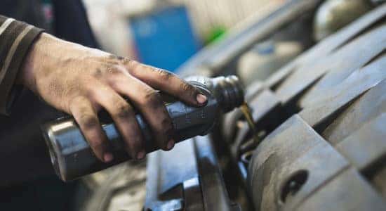 A mechanic refilling the oil chamber after changing out the old oil.