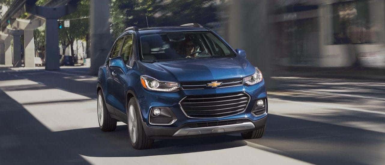 A blue 2021 Chevy Trax is shown from the front driving under a bridge near Lexington, KY.