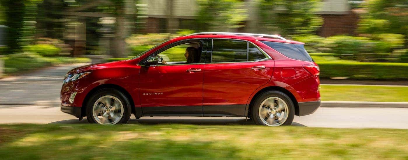 A red 2020 Chevy Equinox is shown from the side while driving in a suburb.