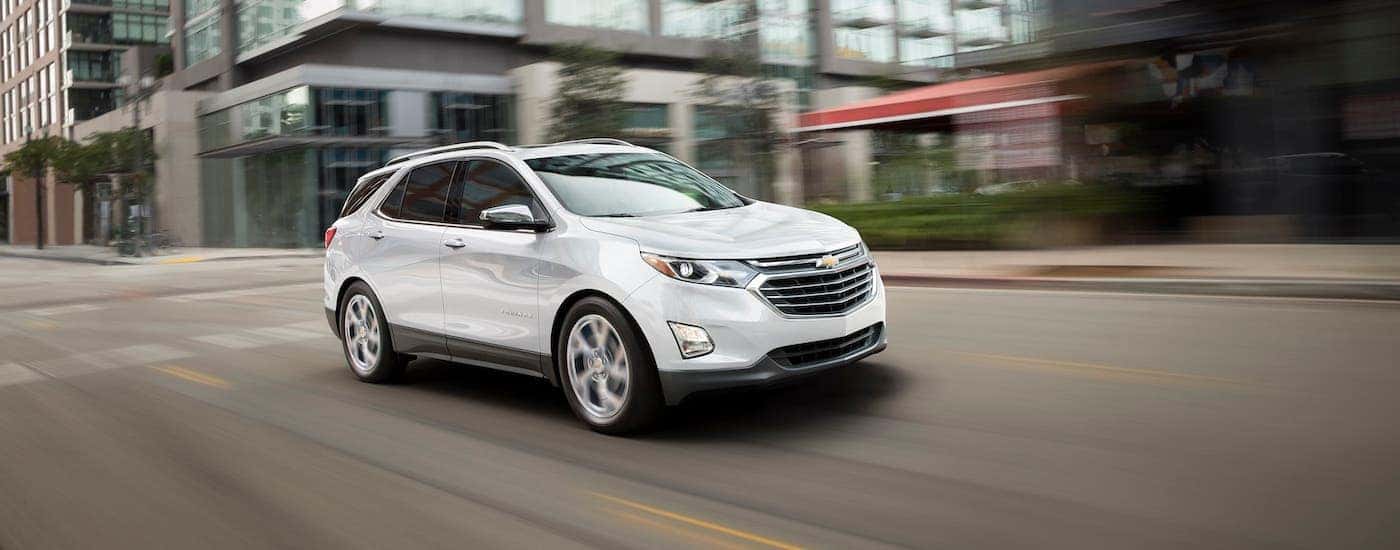A white 2020 Chevy Equinox is driving on a city street.