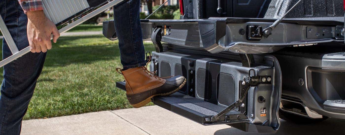 Someone is climbing into the bed using the Multi-Flex tailgate on a gray 2021 Chevy Silverado 1500.