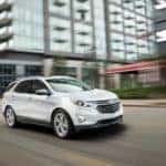 A white 2018 used Chevy Equinox is driving through the city.