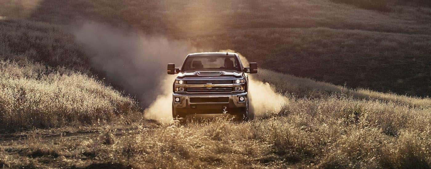 A black 2017 used Chevy Silverado 2500HD is shown from the front driving on a dirt road.
