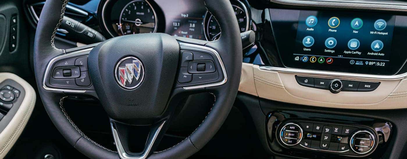 A close up shows the steering wheel and infotainment system on a 2021 Buick Encore GX.