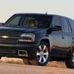 A black 2009 used Chevy Trailblazer is parked in front of sand dunes and beach grass.