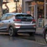 A popular Chevy electric vehicle, a silver 2022 Chevy Bolt EUV, is shown from the rear parked in front of a coffee shop.