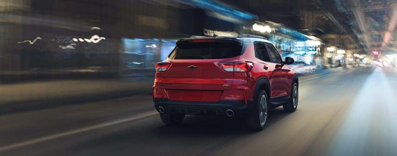 A red 2021 Chevy Trailblazer RS is shown driving from the rear against a blurred background.