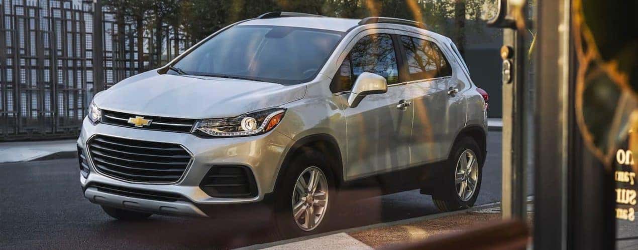 A silver 2022 Chevy Trax is shown from the side through a shop window.