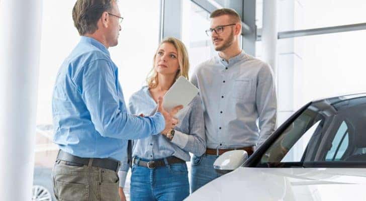 A couple is talking to a salesman at a used car dealership in Lexington.
