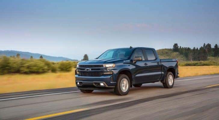 A blue 2019 Chevy Silverado 1500 is driving past a field after leaving a used Chevy truck dealer in Lexington.