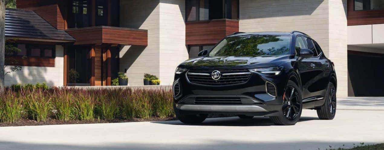 A black 2021 Buick Envision is parked outside of a modern home.