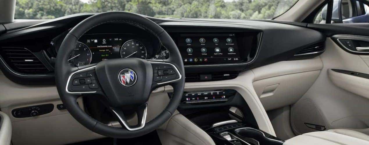 The interior of a 2021 Buick Envision shows the steering wheel and infotainment screen.