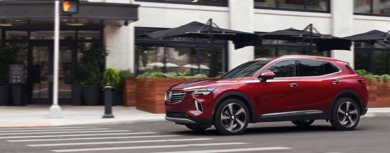 A red 2021 Buick Envision is shown from the side driving past a hotel.