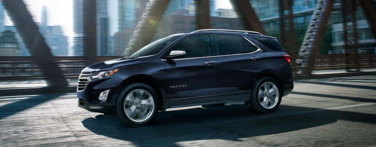 A black 2021 Chevy Equinox is driving over a bridge after winning a 2021 Chevy Equinox vs 2021 Honda CR-V Comparison.