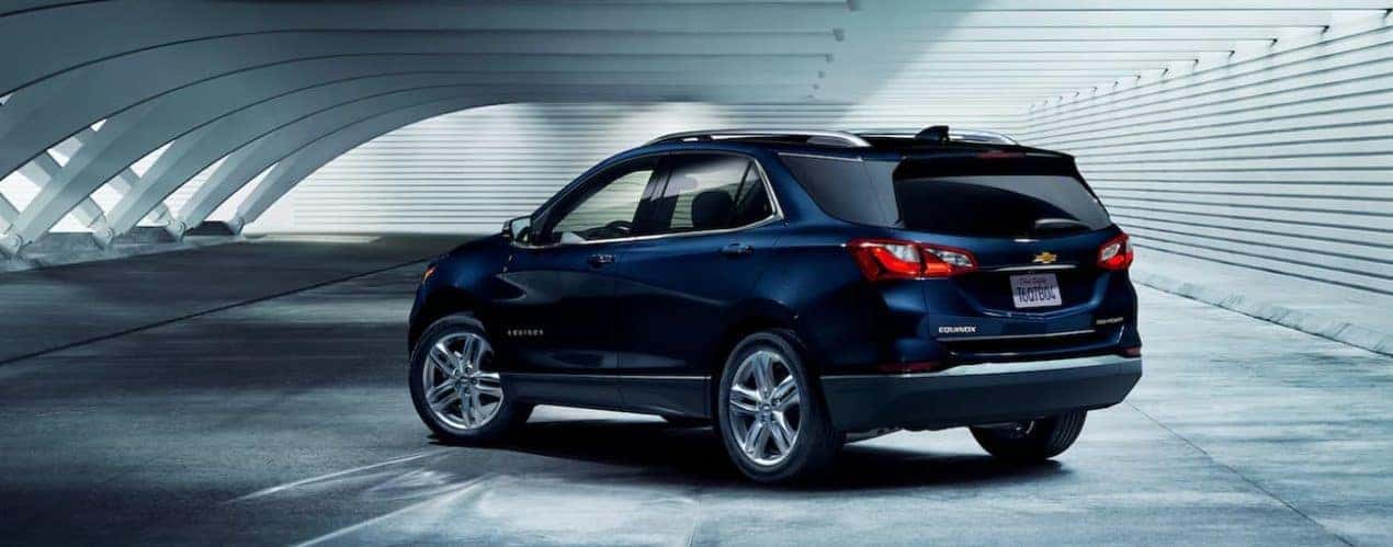 A blue 2021 Chevy Equinox is shown from the side parked in a modern parking garage.