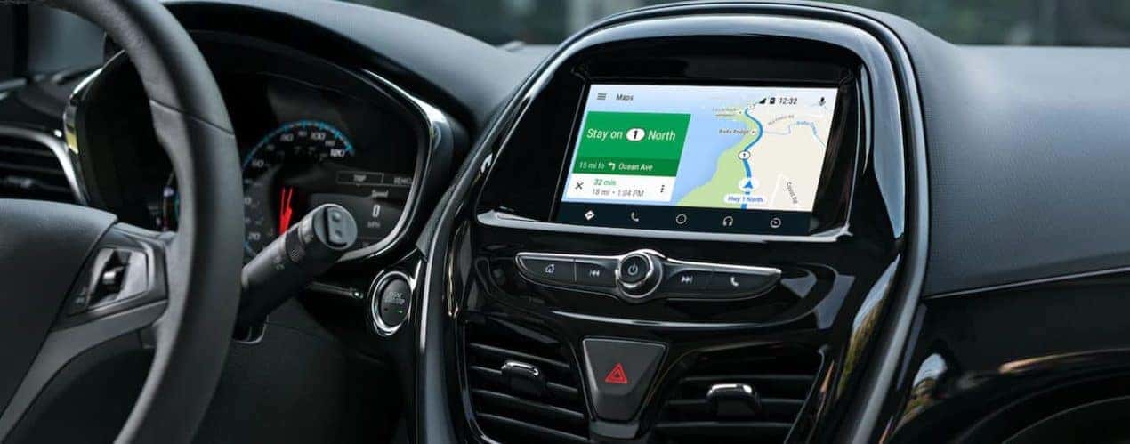 The black interior in a 2021 Chevy Spark shows the steering wheel and infotainment screen.