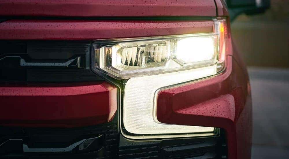 A close-up is shown of a headlight on a red 2023 Chevy Silverado 1500.