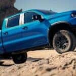 A blue 2024 Chevy Silverado ZR2 for sale is shown driving off-road in a desert.