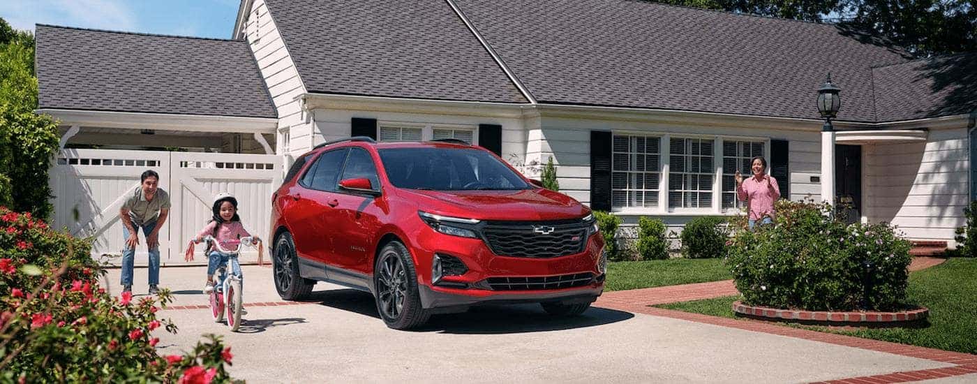 A red 2024 Chevy Equinox RS is shown in a driveway.
