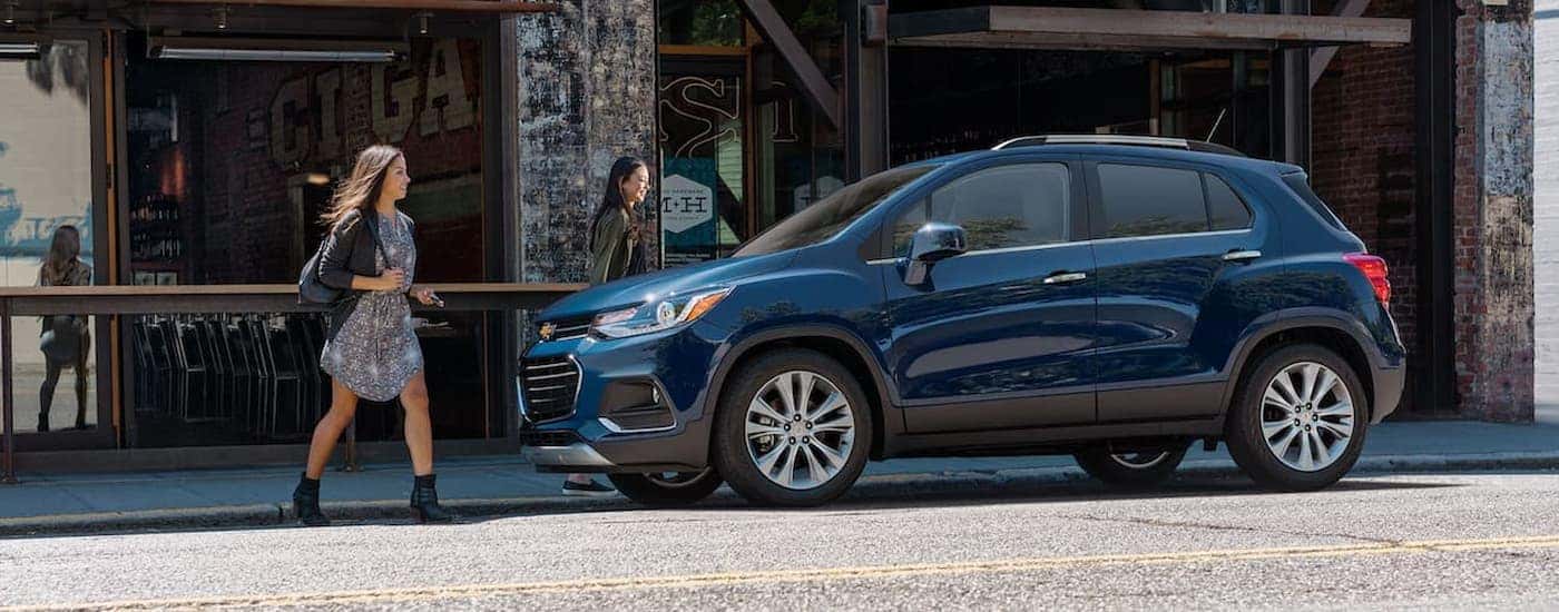 A blue 2020 Chevy Trax is shown parked near a shop.