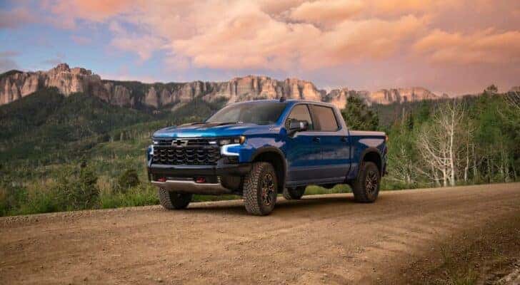 A blue 2023 Chevy Silverado 1500 ZR2 is shown driving on a trail.