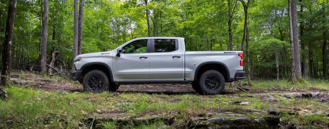 A white 2023 Chevy Silverado 1500 ZR2 is shown from a side angle while parked in a forest.