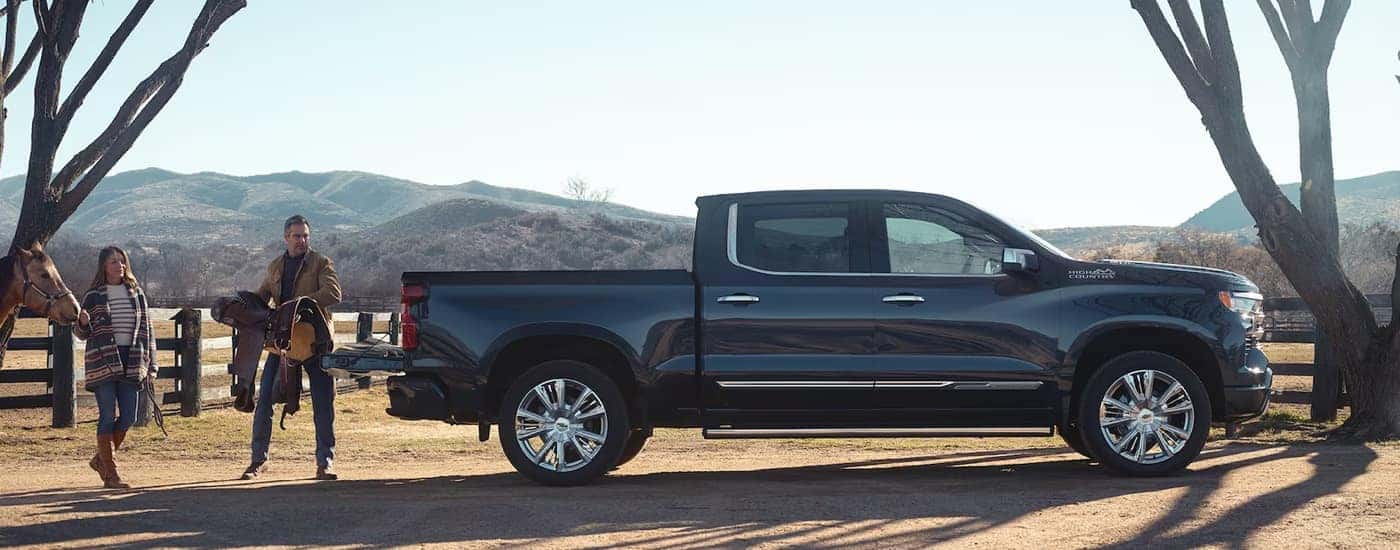 Side view of a black 2024 Chevy Silverado 1500 High Country parked on a horse farm.