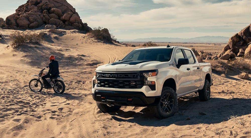 A white 2024 Chevy Silverado 1500 Custom Trail Boss off-roading through sand.