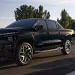 A black 2025 Chevy Silverado EV RST is shown charging after visiting a Chevy Silverado 1500 for sale near Covington.