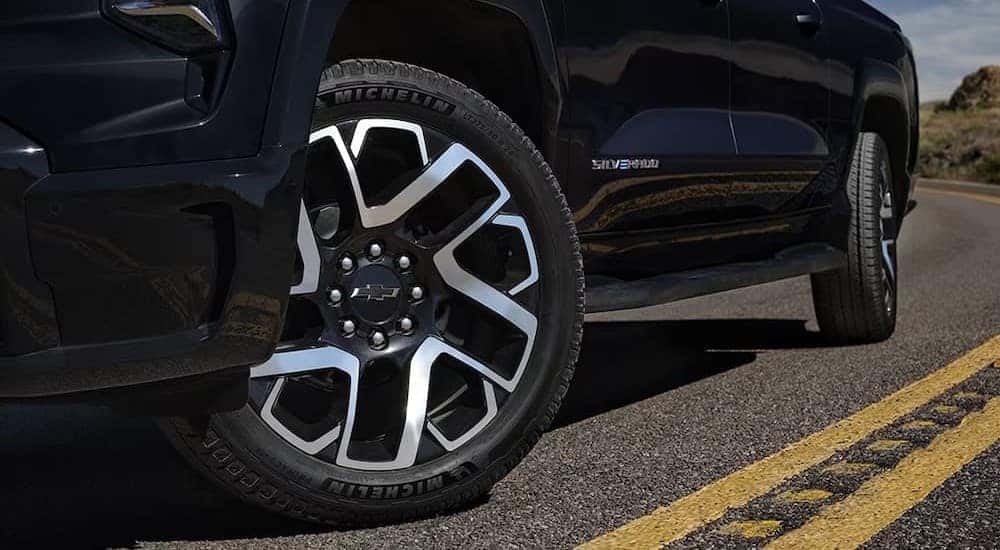A close-up of a wheel on a black 2025 Chevy Silverado EV RST is shown.