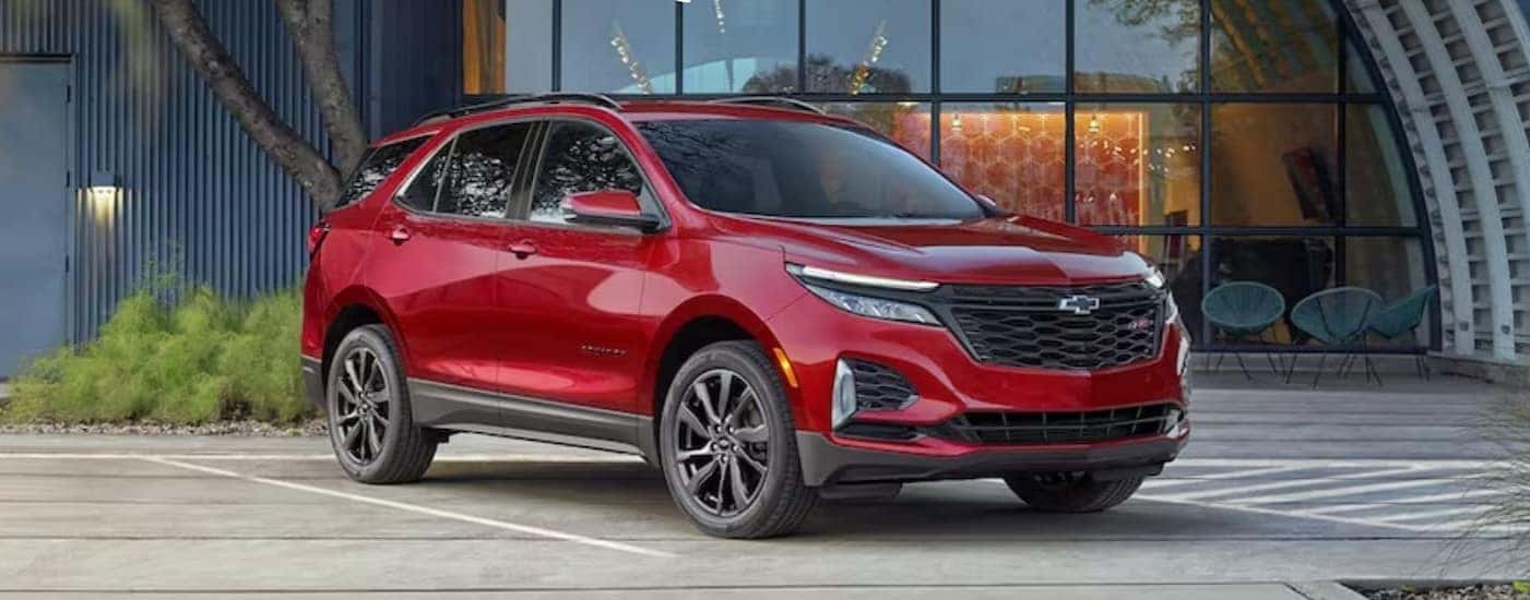 A red 2024 Chevy Equinox RS for sale near Florence is shown parked near a hangar.