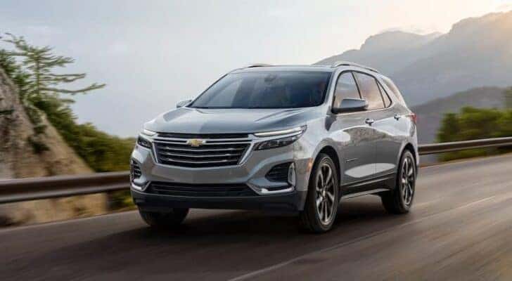 A silver 2024 Chevy Equinox is shown driving to a Chevy dealer near Covington.