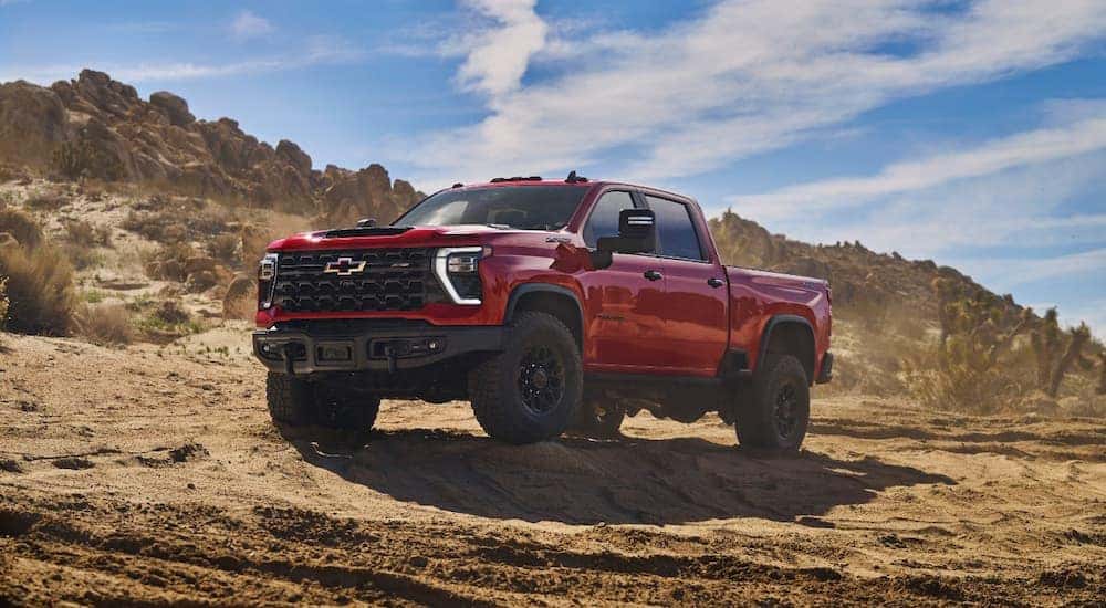 A red 2024 Chevy Silverado 2500 HD ZR2 Bison parked in a rocky area.